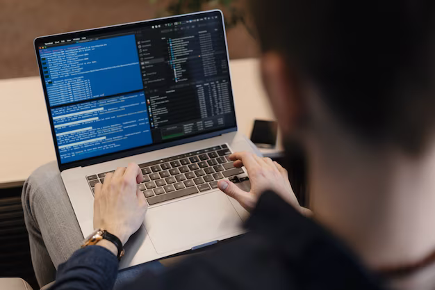 Rear view of a man writing program code on a laptop