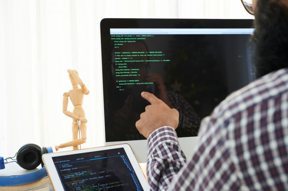 Person pointing at a computer screen with code and a mannequin