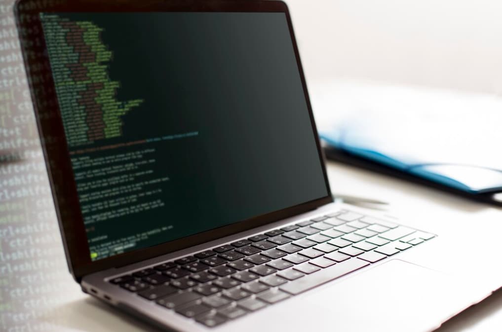 Laptop displaying code on screen with glasses beside it